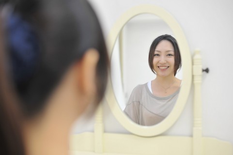 鏡で笑顔をチェックする女性