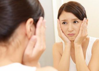 鏡を見てしわに悩む女性
