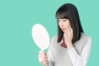 ほうれい線が気になり鏡で確かめる高校生