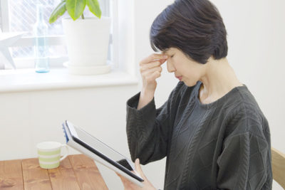 タブレットの使い過ぎでブルーライトの影響で目が疲れている女性