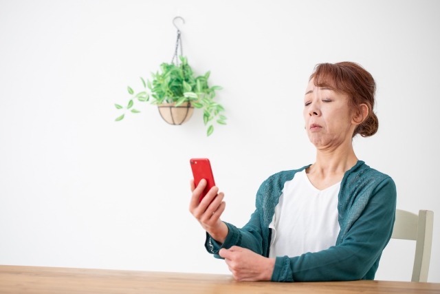 スマホの使いすぎで目が疲れて液晶画面が見づらくなっている女性