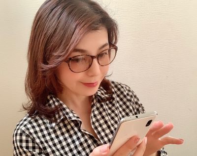 アイケアメガネをつけてスマホを操作する飯塚美香さん