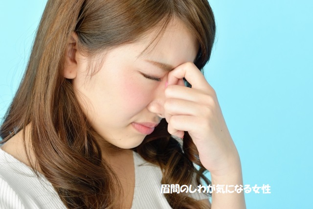 眉間のしわが気になる女性